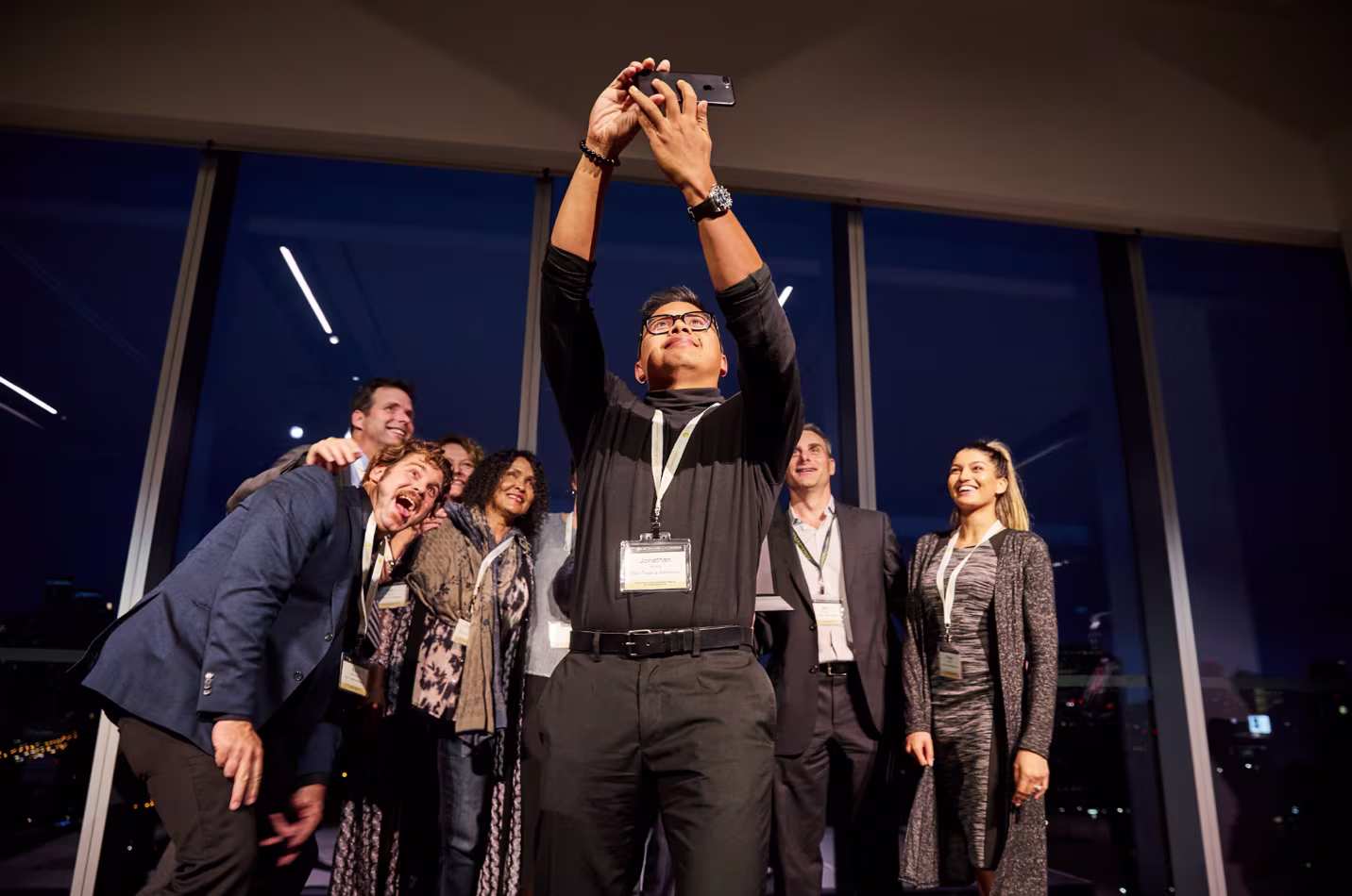 Group of people on stage taking a selfie together at an awards or networking event.